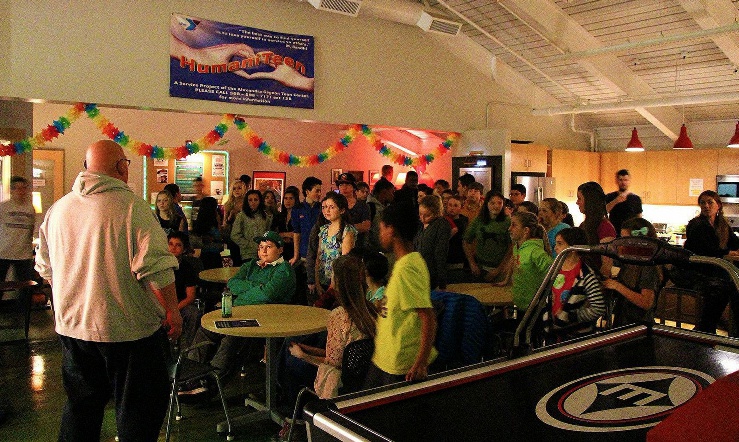 A group of people standing around tables in front of a crowd.